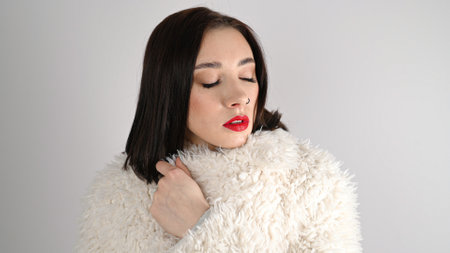 Young woman with great shapes brows, long eyelashes and red lips. Brunette posing on white wall.の写真素材