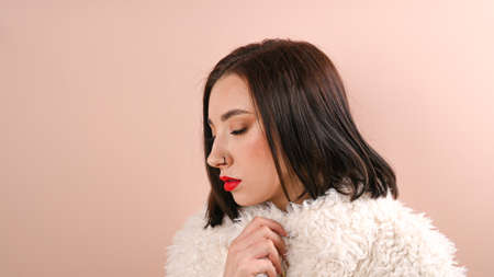 Attractive beautiful girl with closed eyes wears coat of eco on pastel background.の写真素材