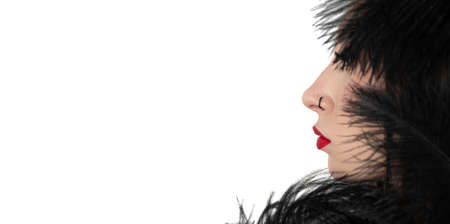 Creative stylish portrait of caucasian model girl with red lips and black feathers around her head, side view. Beauty concept.の写真素材