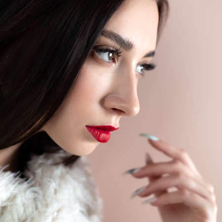 Young woman with great shapes brows, long eyelashes and red lips. Brunette posing on white wall.の写真素材