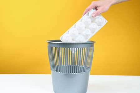 Hand throws out a plastic container for eggs in the trash bin. High quality photoの写真素材