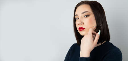 Portrait of a young beautiful brunette with piercings in her nose. On an isolated background.の写真素材
