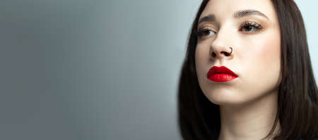 Portrait of a young beautiful brunette with piercings in her nose. On an isolated background.の写真素材