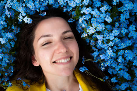 Beautiful young girl smiling on a background of blue flowers.の写真素材