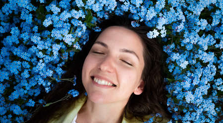 Beautiful young girl smiling on a background of blue flowers.の写真素材