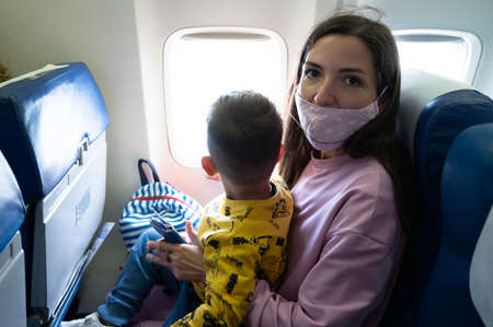 Mother with her baby on her knees on the planeの写真素材