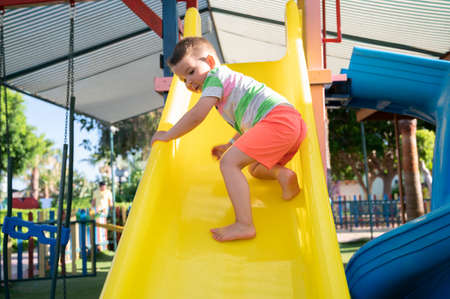 The child is afraid of rolling down the childrens slideの写真素材