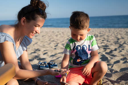Mom chatting with son on the beachの写真素材