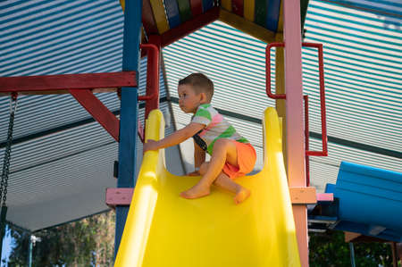 The child is afraid of rolling down the childrens slideの写真素材