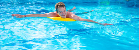 Happy young man swims in the pool.の写真素材