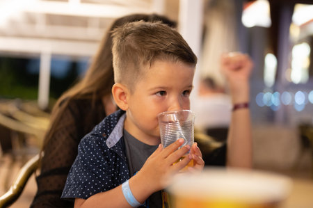 Child drinks a glass of water in a mountain cabin. High quality photoの写真素材