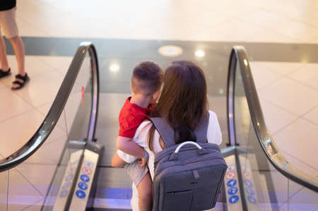Mom with a child in her arms, descend on an escalator.の写真素材