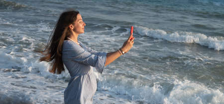 Young woman with phone by the sea.の写真素材