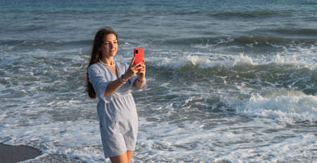 Young woman with phone by the sea.の写真素材