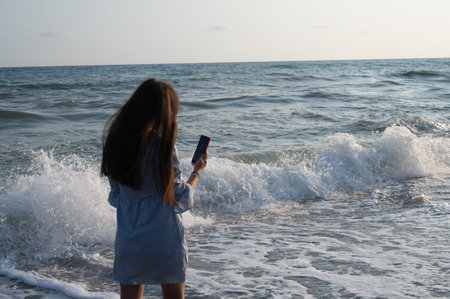 Young woman taking pictures of herself against the background of the sea.の写真素材