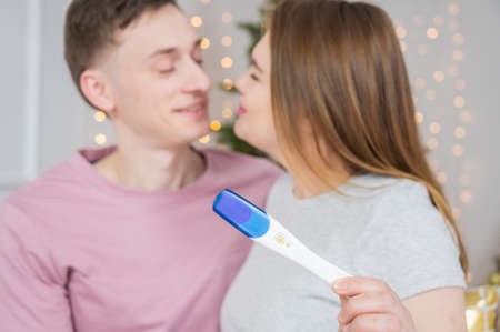 Happy young couple showing pregnancy test together.の写真素材