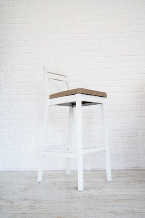 High white wooden stool on a white brick wall background wiht copy space.の写真素材