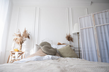 Stylish interior of comfortable bedroom. Cozy apartment in soft beige and white colorsの写真素材