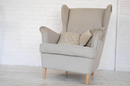 Biege cozy armchair with pillow in room. Minimalist interior conceptの写真素材