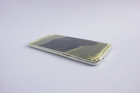 Modern mobile phone with broken screen on white background.の写真素材