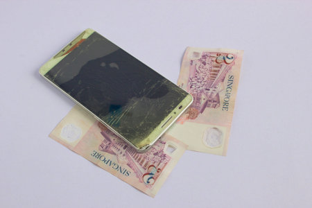 Modern mobile phone with broken screen on white background. Singapore dollarの写真素材