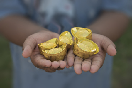 Chinese new year ornament--Stack of gold ingots. Boy holding gold extended. Translation in English meaning lucky and richlyの写真素材