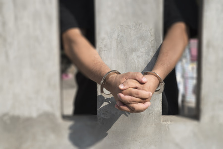 Human hand of prisoner on steel lattice close up. no freedomの写真素材