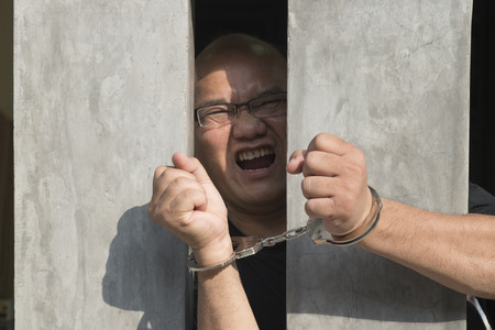 Human hand of prisoner on steel lattice close up. no freedomの写真素材