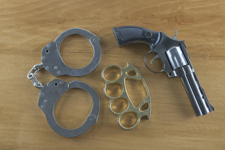 Gun handcuffs brass knuckles on the wooden floorの写真素材