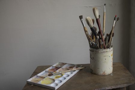 Paint brushes with a palette on wooden table.の写真素材