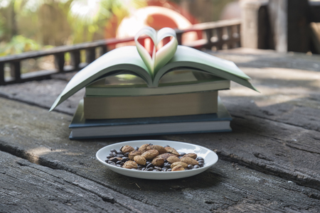 Almonds on wooden table.Pages of a book curved into a heart shape,Book page in heart shape with bokeh background.の写真素材