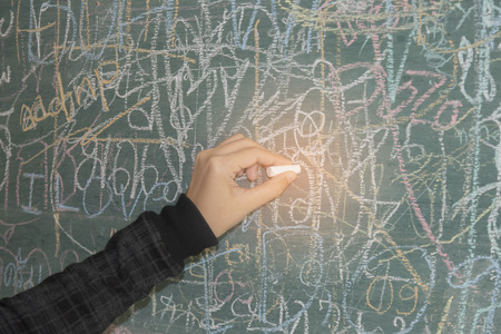 Female hand writing on blackboard with selective and soft focusの写真素材