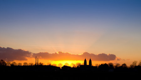 nice sunset with a silhouette of a village with church towers の写真素材