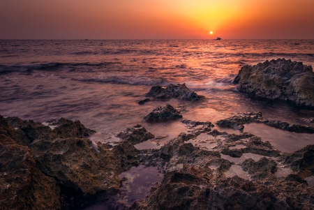red sunset over the sea with rocks in foregroundの写真素材