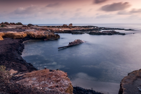 rocky beach with shipwreck on cloudy morgningの写真素材