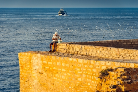 Fisherman on the Sea Gives Bait on the Old Fishing Hookの写真素材