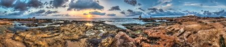 sunset over the sea and rocky coast with ancient ruinsの写真素材