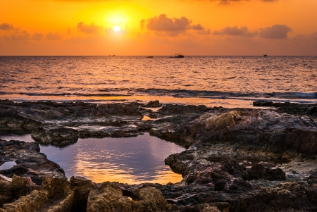 sunset over the sea and rocky coast with trawlerの写真素材