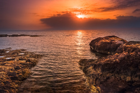 Sunset over the Sea and Rocky Beachの写真素材