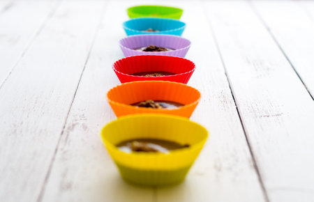 Chocolate Truffles in Colorful Cups in a Row on White Wooden Tableの写真素材
