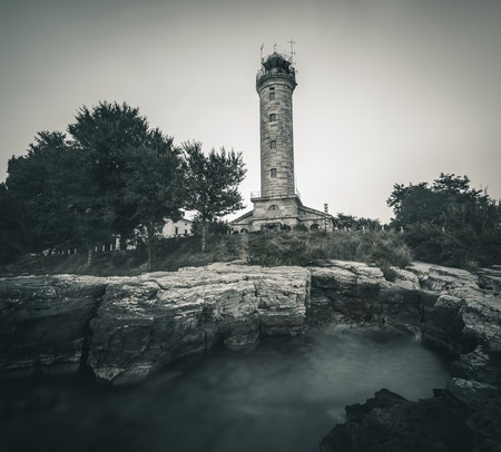 Savudrija Lighthouse on Rocky Coast, the Most Western Point of the Balkans Peninsula and the Oldest Lighthouse in Croatia Built 1818. Black and White.の写真素材