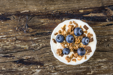 Serving of Yogurt with Whole Fresh Blueberries and Muesli on Old Rustic Wooden Table. Closeup Detail. Copy Space.の写真素材