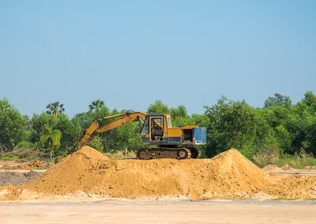Old Excavator on Sand with forest in the Background and Blue Sky