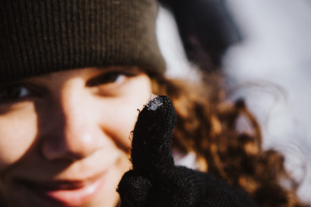 young woman showing a snowflake on her glove