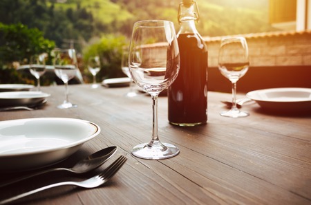 bottle of wine and wine glasses on a table outdoors during sunsetの写真素材
