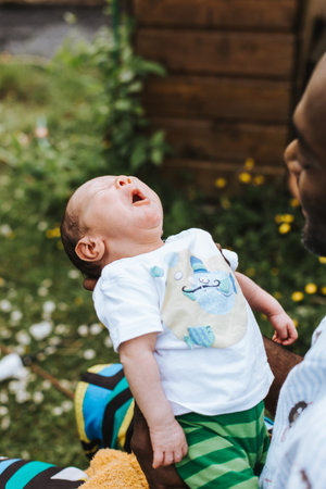 black father holding yawning his mixed race baby boy