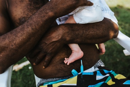 Strong arms of a black father carrying his mixed race baby boyの写真素材
