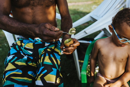 father offers his son to feed him a kiwi fruit and denies