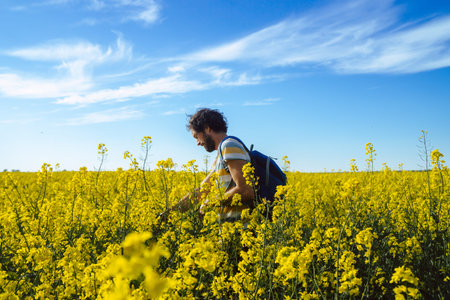 Young caucasian man walking through field of rapeseed