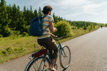 young caucasian man biking through the nature with smartphone in his hands to navigateの写真素材